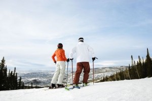Rear view of skiers on ski slope with mountains in background. Horizontal shot.